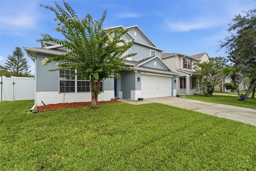A two-story blue house with a white garage and a tree in the front yard — 9773 BENNINGTON CHASE DRIVE, ORLANDO, FL