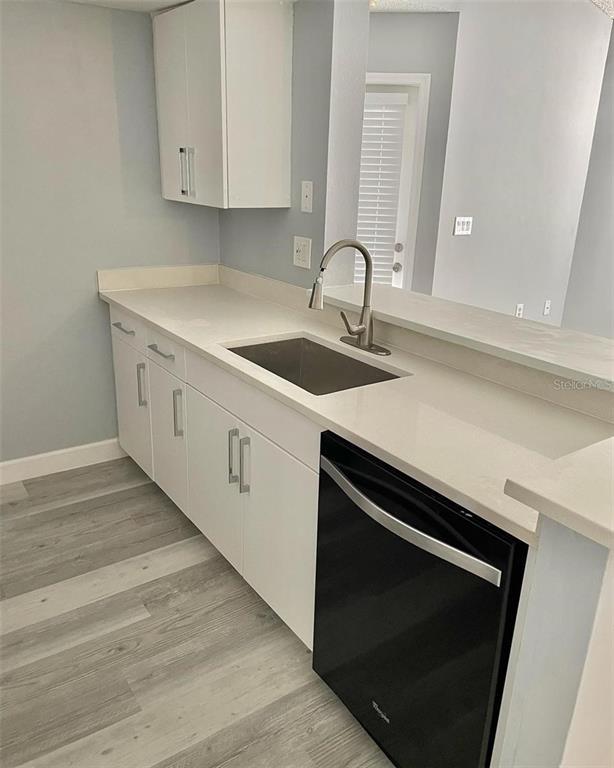 A kitchen features white cabinets, a stainless steel sink, and a black dishwasher — 425 FOUNTAINHEAD CIRCLE UNIT 208, KISSIMMEE, FL
