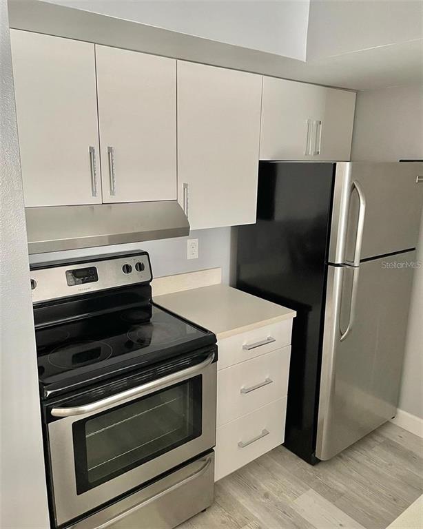 A kitchen features white cabinets, stainless steel appliances, and light-colored countertops — 425 FOUNTAINHEAD CIRCLE UNIT 208, KISSIMMEE, FL