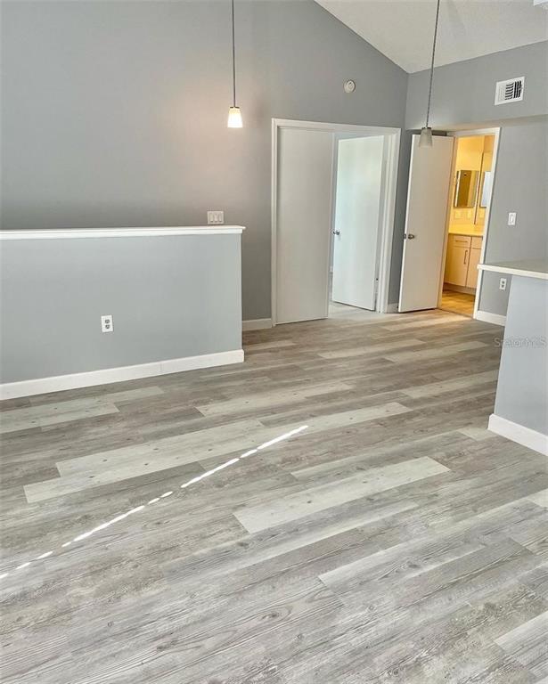 A room with light gray walls, wood-look flooring, and two doorways leading to a bathroom — 425 FOUNTAINHEAD CIRCLE UNIT 208, KISSIMMEE, FL