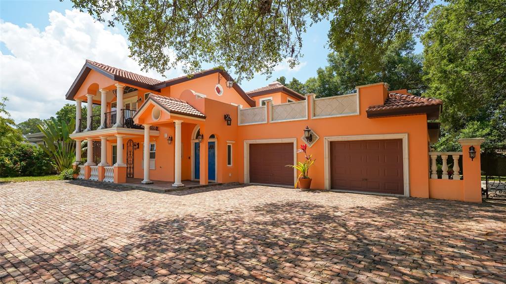 A two-story orange house with a brick driveway, two garage doors, and a covered porch — 2520 TAMI SOLA STREET, SARASOTA, FL