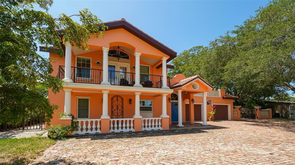 A two-story peach-colored house features a brick driveway, white columns, and a balcony — 2520 TAMI SOLA STREET, SARASOTA, FL