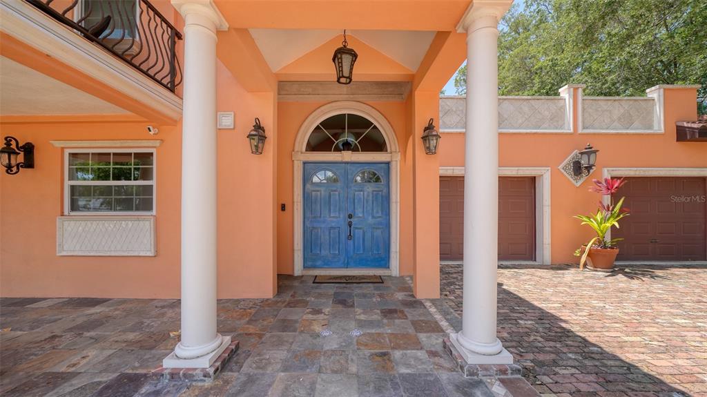 The exterior entrance features a blue double door, two white columns, and a brick driveway — 2520 TAMI SOLA STREET, SARASOTA, FL