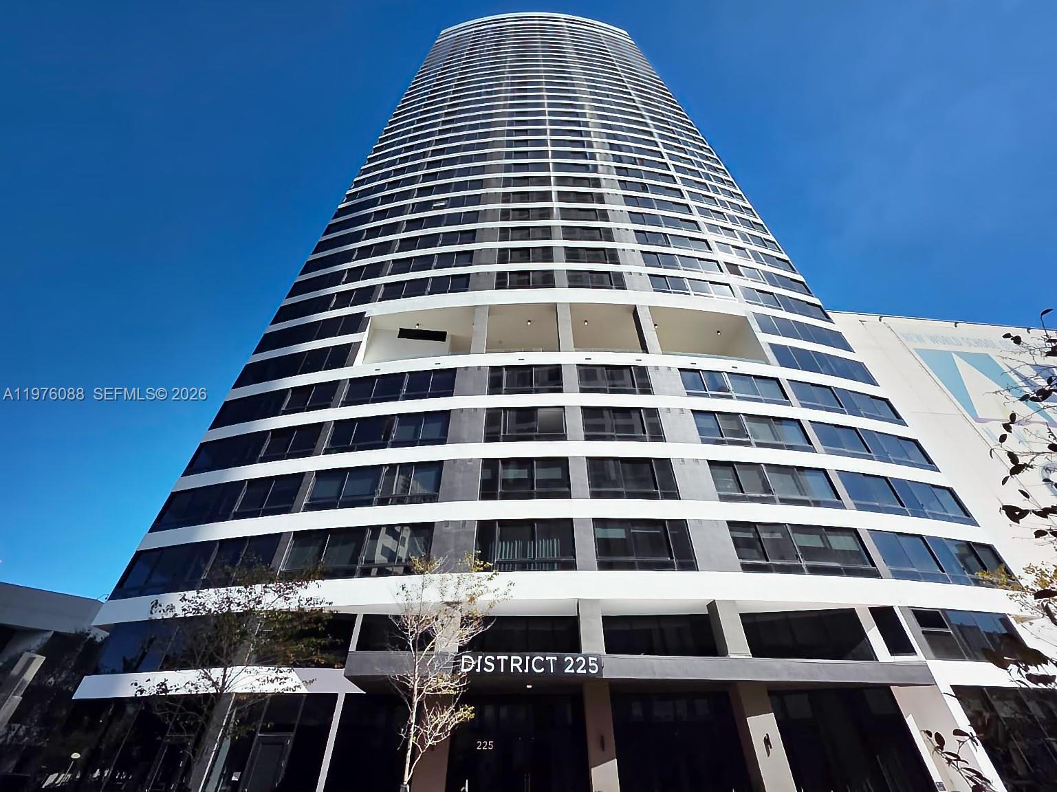 A low-angle exterior view of the District 225 high-rise building against a clear blue sky — 225 N Miami # 3009, Miami FL 33128, MIAMI, FL