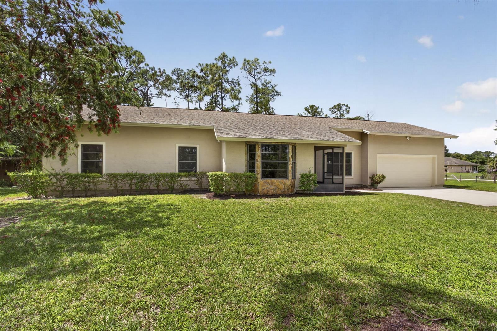 A single-story house with a beige stucco exterior, a stone-accented bay window, and a garage — 6045 Hall Boulevard, FL 33470, FL