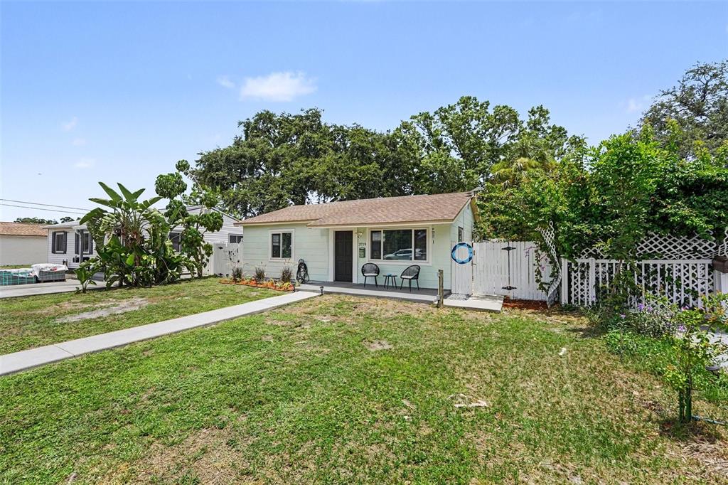A light green single-story house with a front porch and a white picket fence — 3719 39TH STREET N, ST PETERSBURG, FL