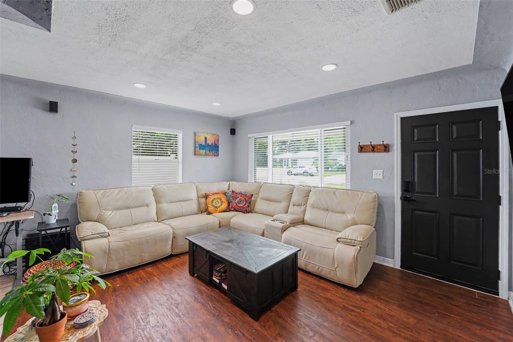 A living room features a beige sectional sofa, a dark coffee table, and wood flooring — 3719 39TH STREET N, ST PETERSBURG, FL