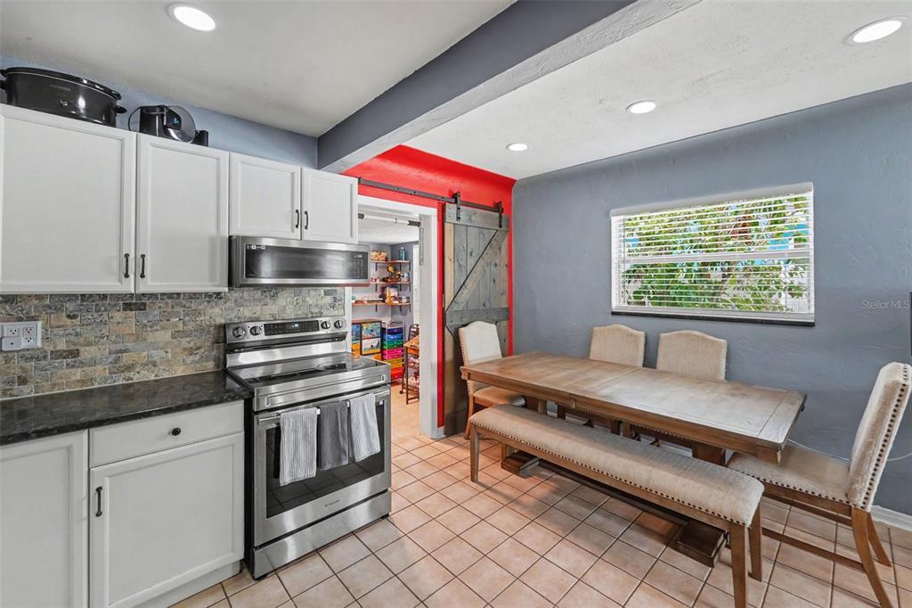 A kitchen with white cabinets, stainless steel appliances, and a dining area with a bench — 3719 39TH STREET N, ST PETERSBURG, FL