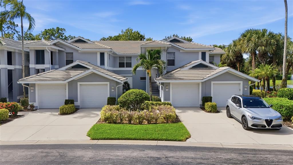 A two-story residential building features four garage bays and a silver car parked outside — 710 TARPON COVE DRIVE UNIT 203, NAPLES, FL