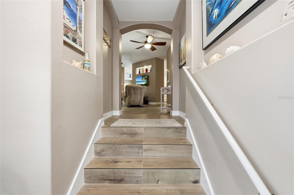 A set of wood-look tiled stairs leads from a hallway into a living area — 710 TARPON COVE DRIVE UNIT 203, NAPLES, FL