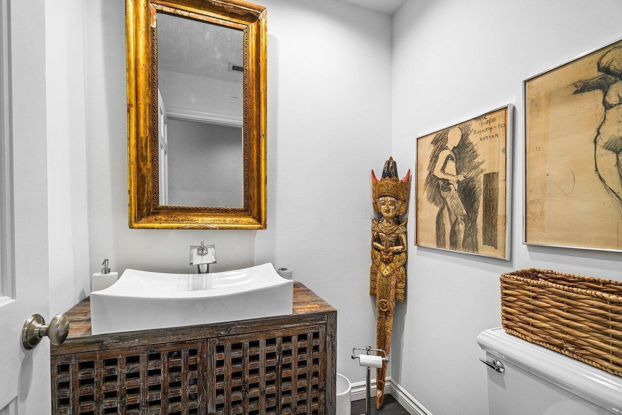 A powder room features a vessel sink on a wooden vanity and decorative wall art — 11823 Pebblewood Drive, Wellington FL 33414, WELLINGTON, FL