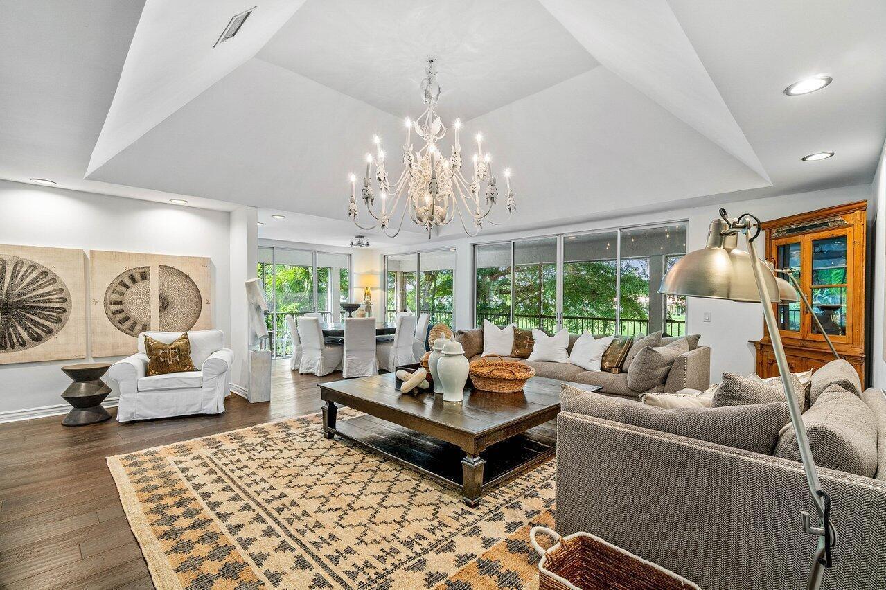 A spacious living room features a vaulted ceiling, a large chandelier, and a patterned rug — 11823 Pebblewood Drive, Wellington FL 33414, WELLINGTON, FL