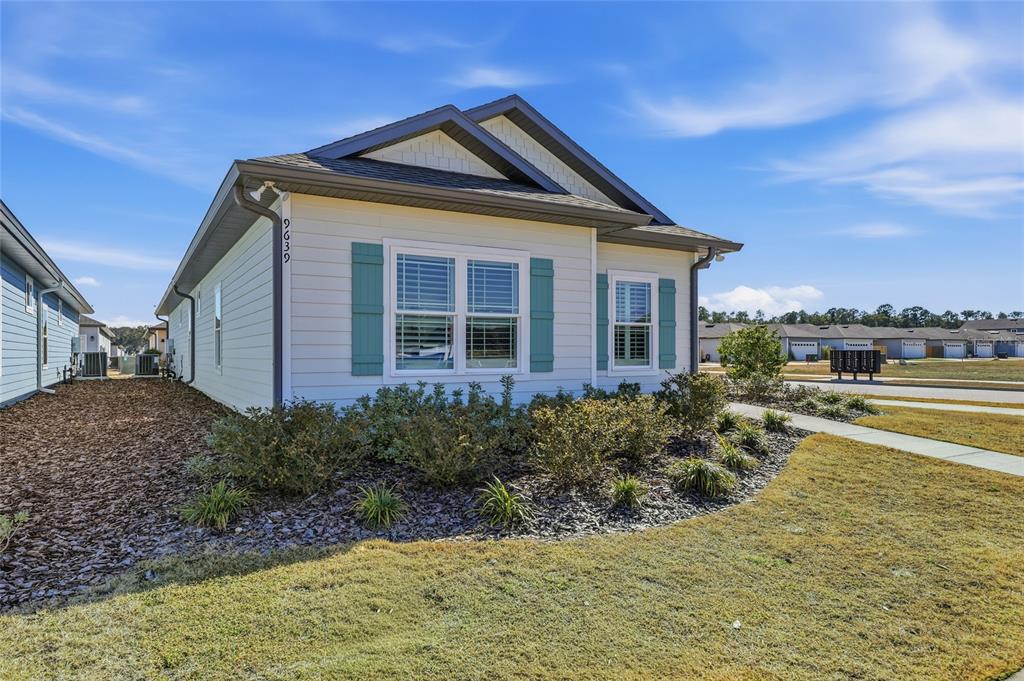A single-story house with white siding, teal shutters, and a dark shingled roof — 9639 SW 66TH LANE, GAINESVILLE, FL