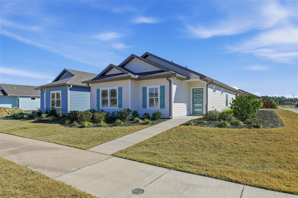 A light-colored single-story house with blue shutters and a teal front door — 9639 SW 66TH LANE, GAINESVILLE, FL