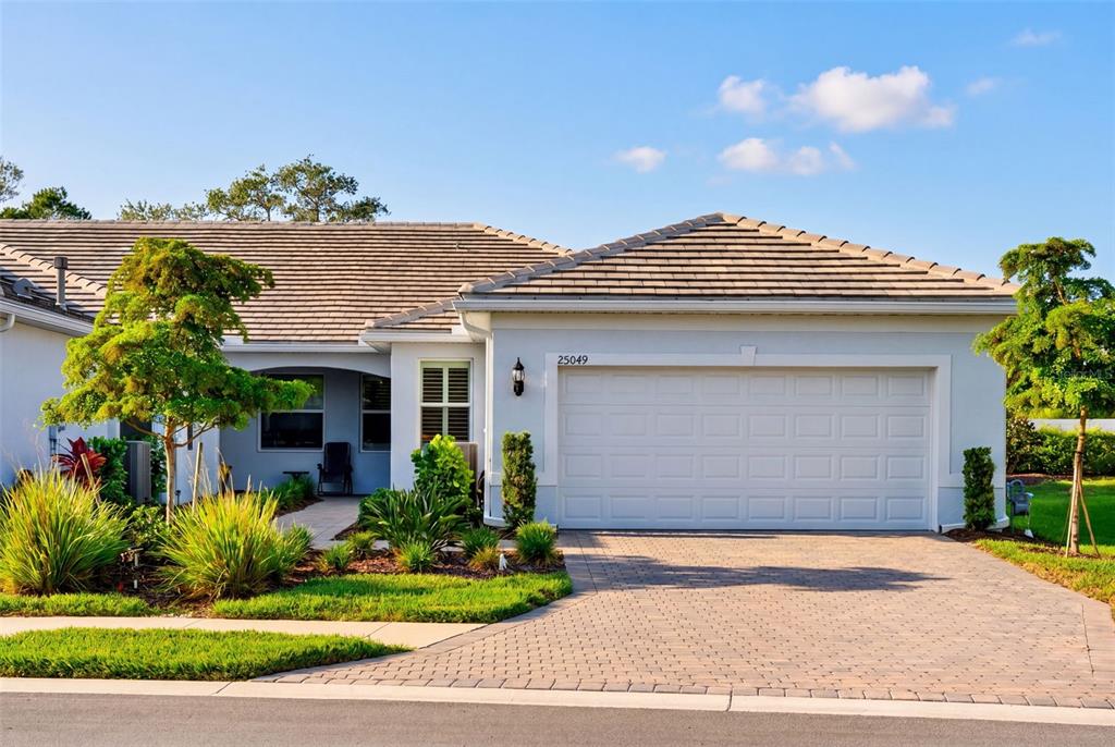A single-story house with a white exterior, a two-car garage, and a paved driveway — 25049 PEARL LAKE CIRCLE, ENGLEWOOD, FL