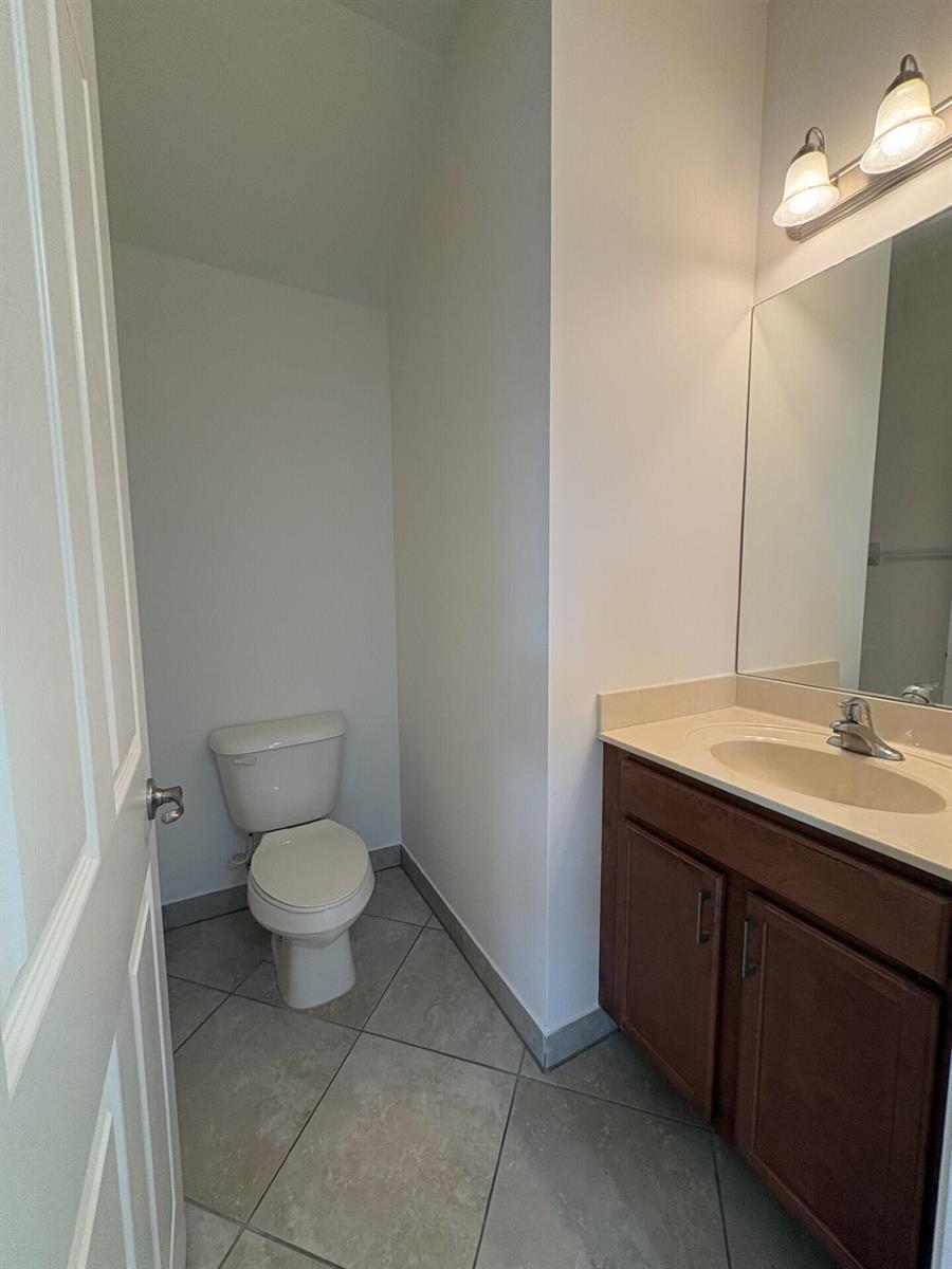 A bathroom features a toilet, a vanity with a sink, and a wall-mounted mirror — 8187 Half Dome Court, Boynton Beach FL 33473, BOYNTON BEACH, FL