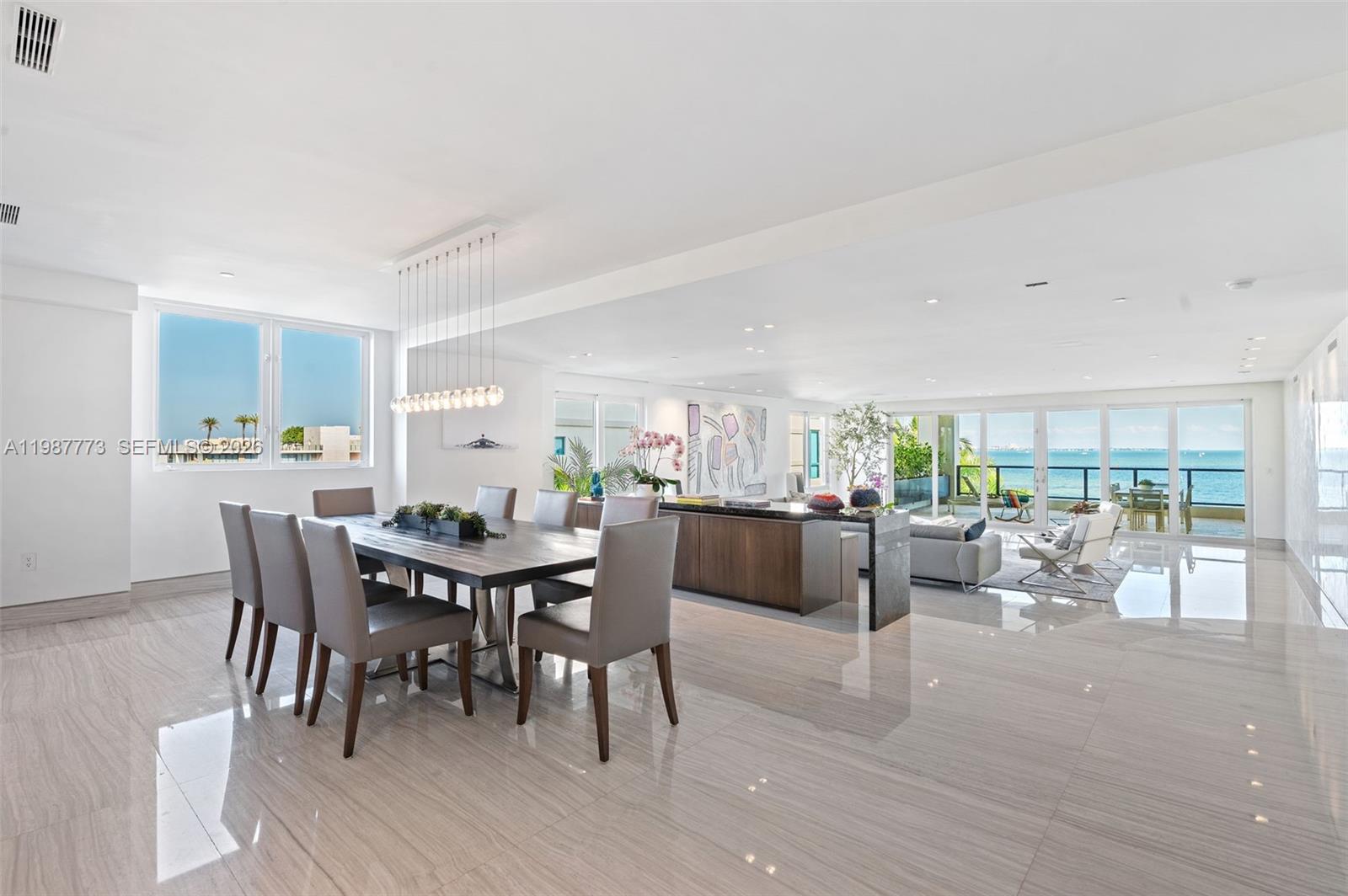 A dining area and living room with marble floors and floor-to-ceiling windows overlooking the ocean — 3535 Hiawatha Ave # 502, Miami FL 33133, MIAMI, FL