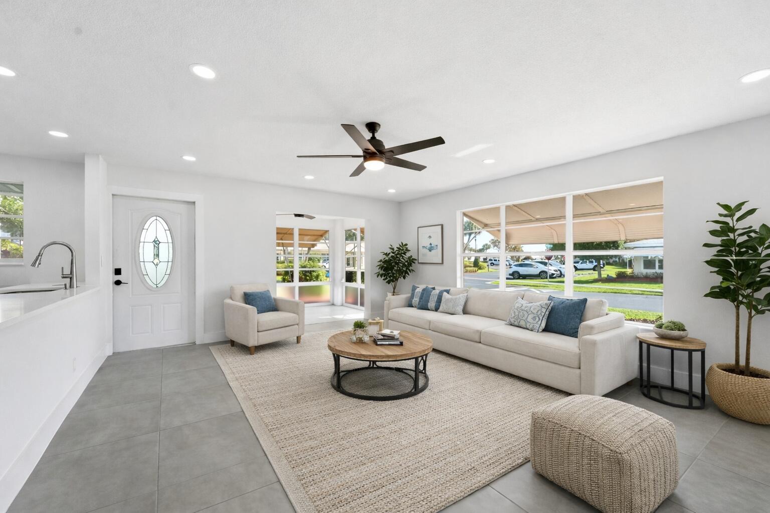 A bright living room features gray tile floors, a white sofa, and a round coffee table — 203 Manatee Lane # A, Fort Pierce FL 34982, FORT PIERCE, FL