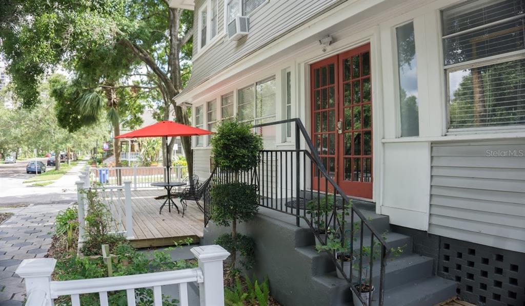 A house exterior features a wooden deck with a red umbrella and gray concrete steps — 700 1ST STREET N UNIT 4, ST PETERSBURG, FL