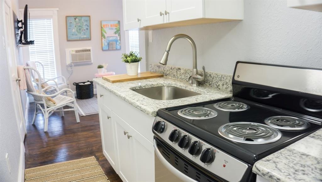 A kitchen with white cabinets, granite countertops, and a black electric stove — 700 1ST STREET N UNIT 4, ST PETERSBURG, FL