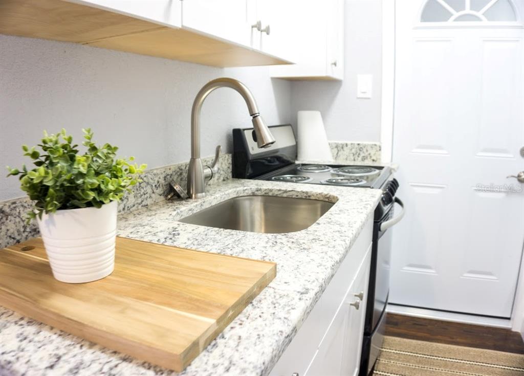 A kitchen features white cabinets, granite countertops, a stainless steel sink, and a black stove — 700 1ST STREET N UNIT 4, ST PETERSBURG, FL