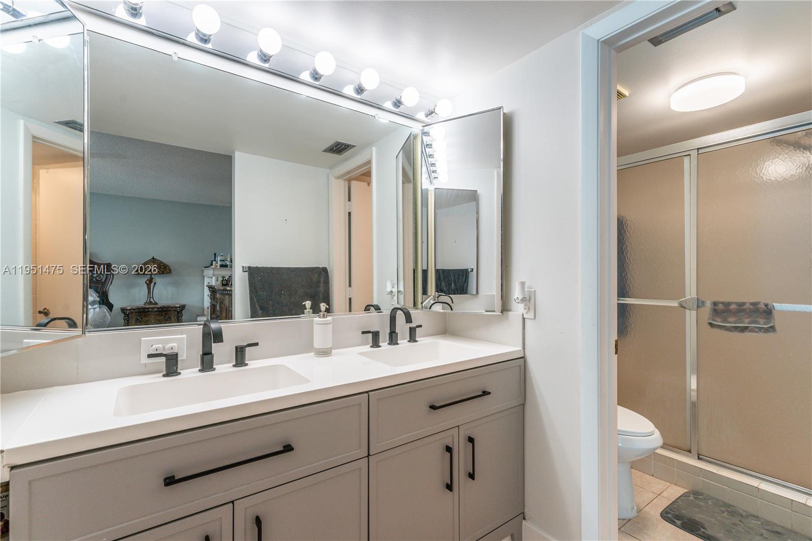 A bathroom features a double vanity with grey cabinets, matte black fixtures, and a large mirror — 4960 E Sabal Palm Blvd # 301, Tamarac FL 33319, TAMARAC, FL