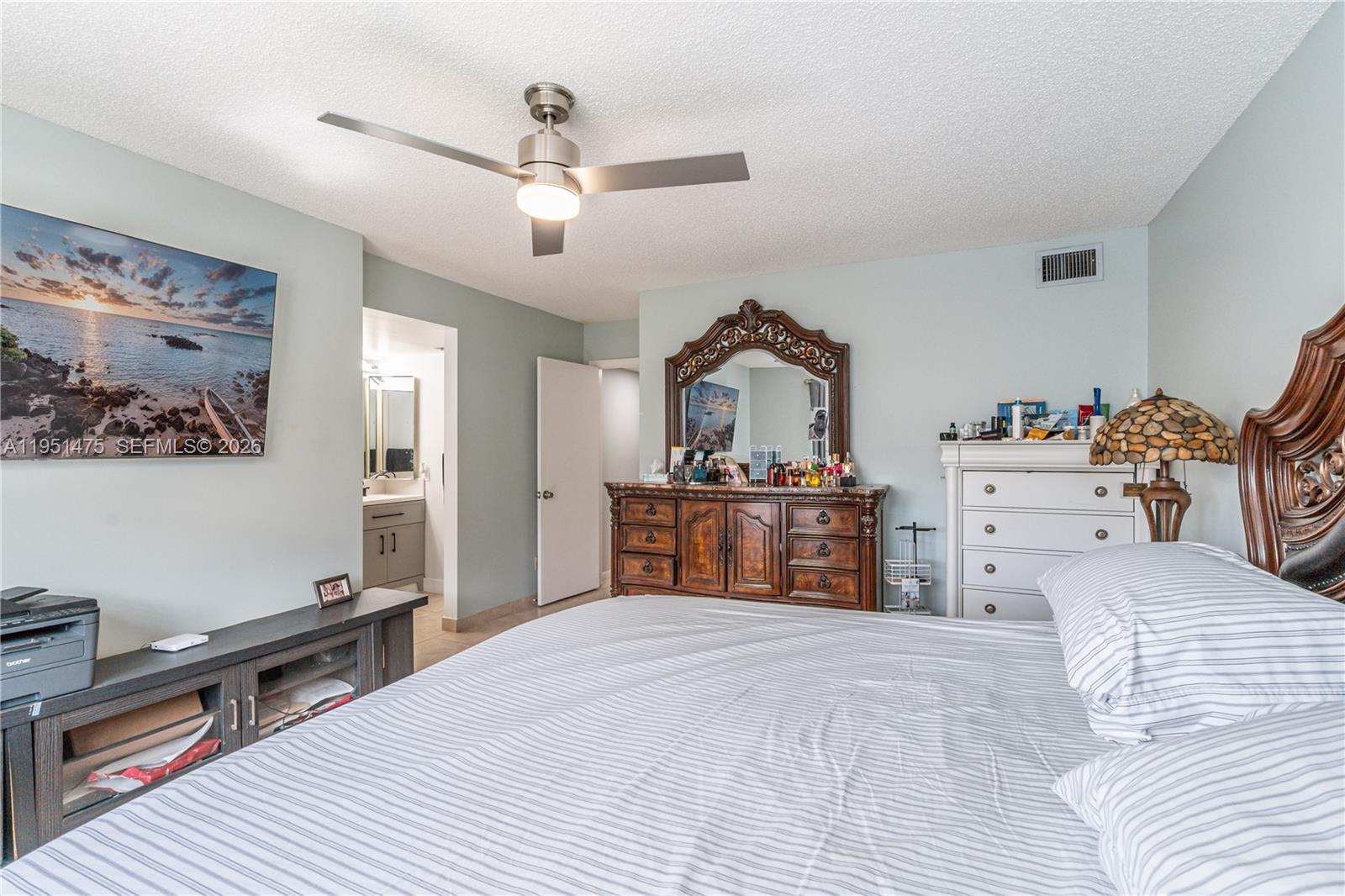 A bedroom features a ceiling fan, a television, a wooden dresser with a mirror, and a bed — 4960 E Sabal Palm Blvd # 301, Tamarac FL 33319, TAMARAC, FL