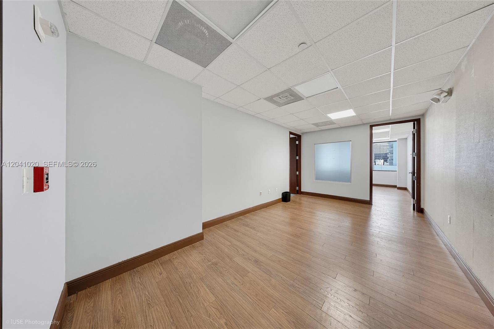 An empty office space features light wood-look flooring, white walls, and a drop ceiling — 1200 Brickell Ave # D, Miami FL 33131, MIAMI, FL