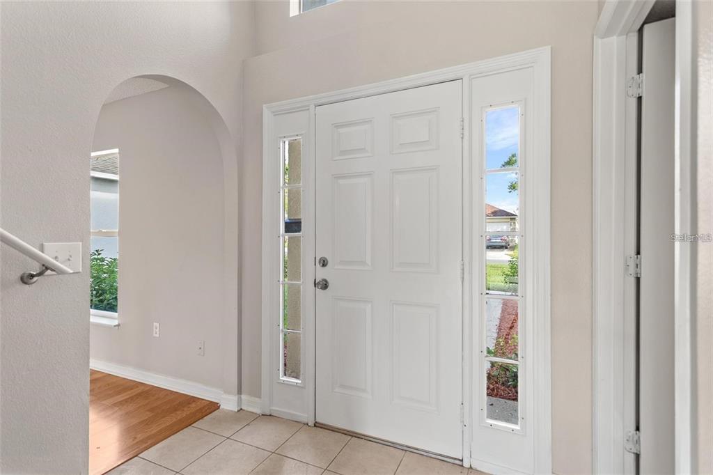 An entryway features a white front door with sidelights, tiled flooring, and an arched opening — 14126 ECON WOODS LANE, ORLANDO, FL