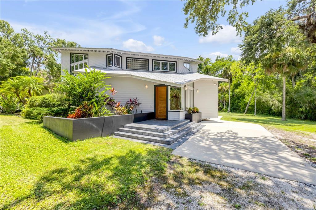 A two-story house with white siding, a metal roof, and a concrete front patio — 2612 TURNBULL BAY ROAD, NEW SMYRNA BEACH, FL