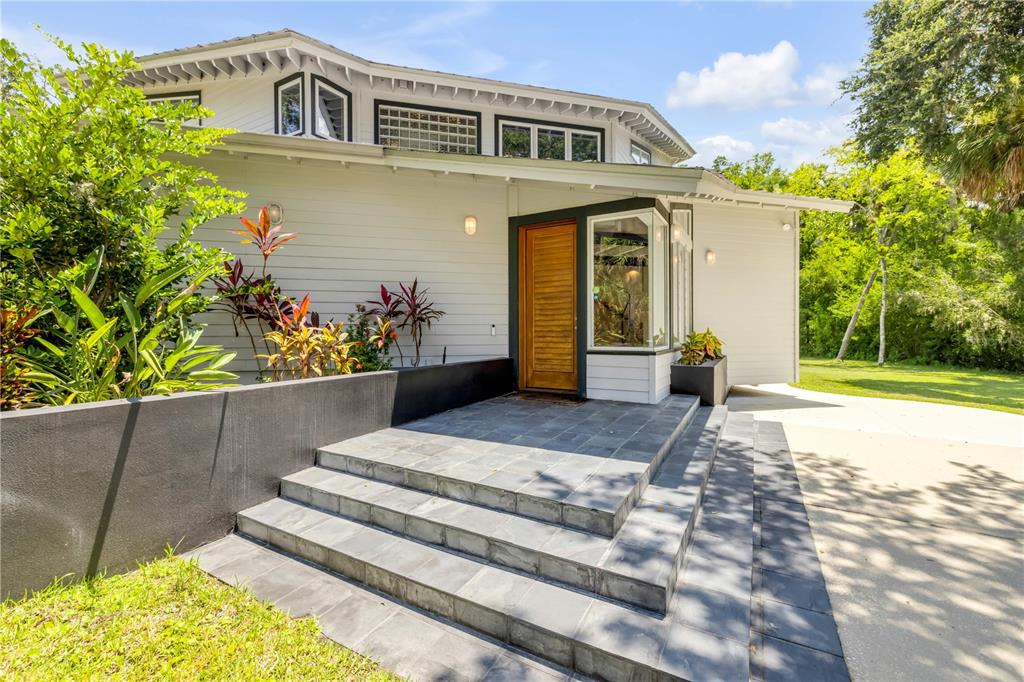 A modern house exterior features a wooden front door, slate steps, and a black planter — 2612 TURNBULL BAY ROAD, NEW SMYRNA BEACH, FL