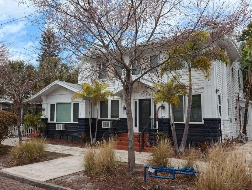 A two-story house with white siding, a dark stone base, and palm trees in front — 255 6TH AVENUE N, ST PETERSBURG, FL