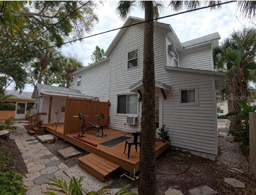 A white two-story house features a wooden deck with a weight bench and palm trees — 255 6TH AVENUE N, ST PETERSBURG, FL