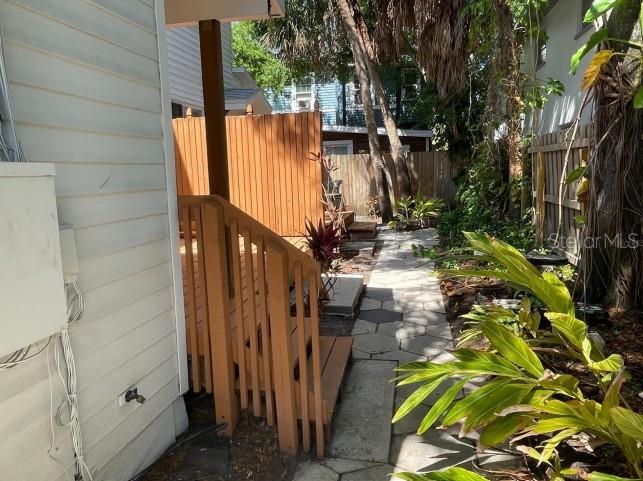 A wooden staircase leads to a deck beside a stone walkway and lush garden foliage — 255 6TH AVENUE N, ST PETERSBURG, FL