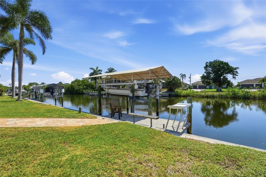 A boat lift with a canopy sits over a canal next to a grassy lawn — 4310 PALM DRIVE, PUNTA GORDA, FL