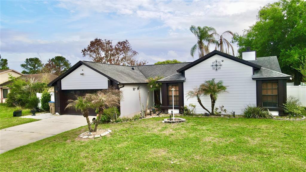 A single-story house with white horizontal siding, a dark roof, and a front-facing garage — 125 TEAKWOOD DRIVE, KISSIMMEE, FL