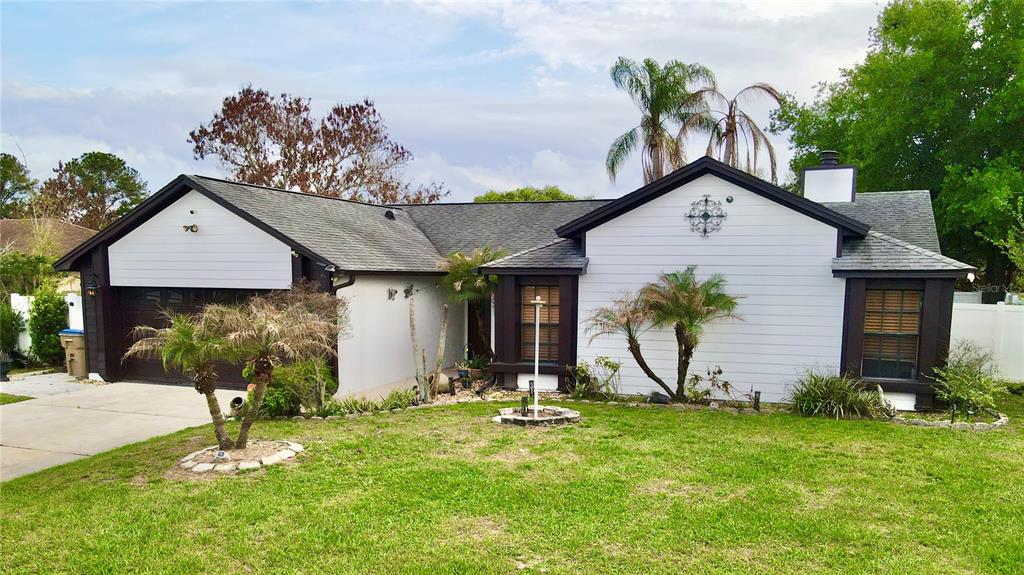 A single-story house with white siding, dark trim, a garage, and a front lawn — 125 TEAKWOOD DRIVE, KISSIMMEE, FL