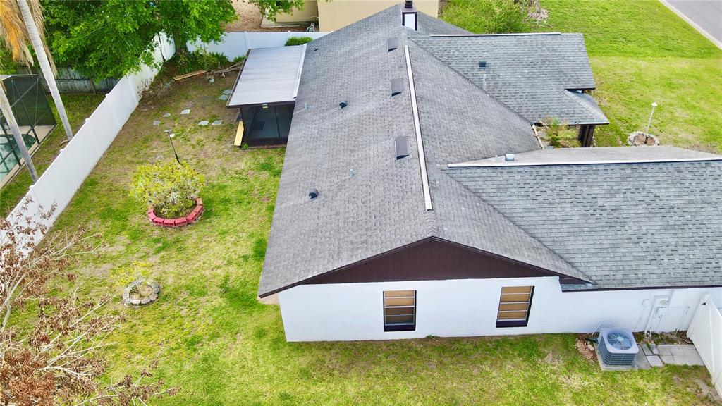 An aerial view shows the shingled roof and white exterior walls of a residential house — 125 TEAKWOOD DRIVE, KISSIMMEE, FL