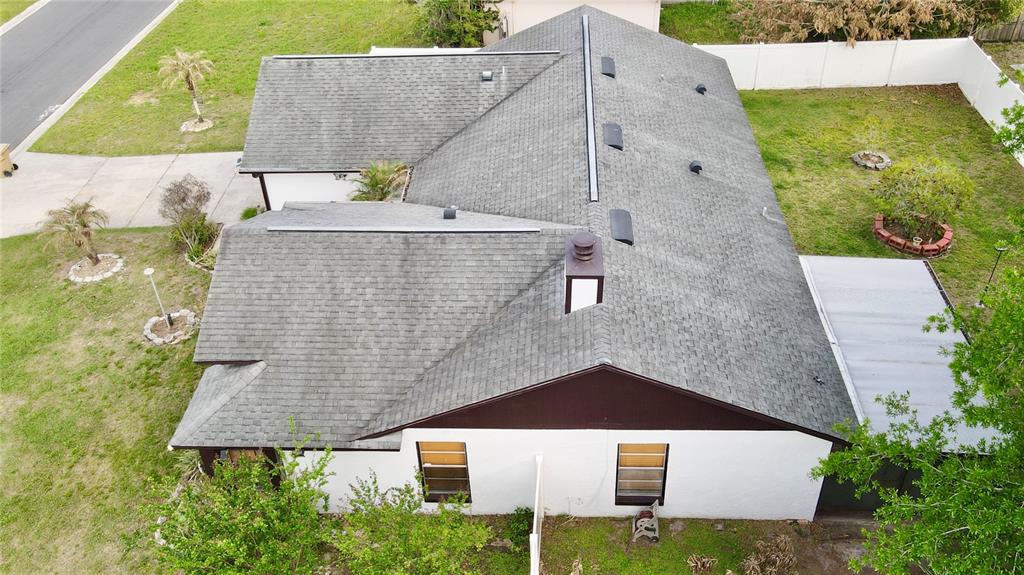 An aerial view of a single-story house with a gray shingled roof and white walls — 125 TEAKWOOD DRIVE, KISSIMMEE, FL