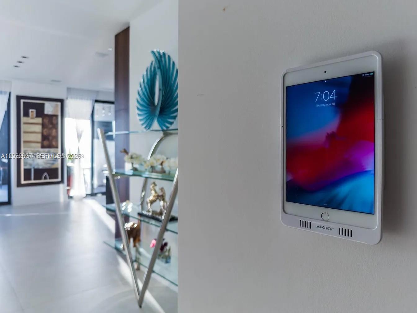 A wall-mounted tablet in a white frame is displayed in a bright, modern hallway — 17141 Collins Ave # 4602, Sunny Isles Beach FL 33160, SUNNY ISLES BEACH, FL