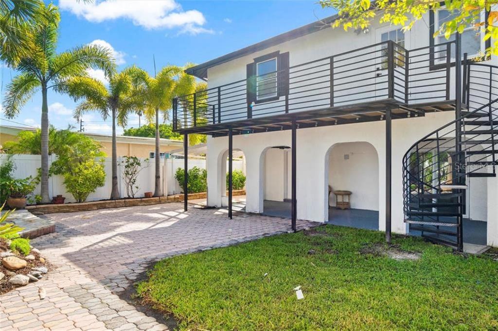 A white two-story house features a metal balcony, a spiral staircase, and a paved patio — 307 161ST AVENUE, REDINGTON BEACH, FL