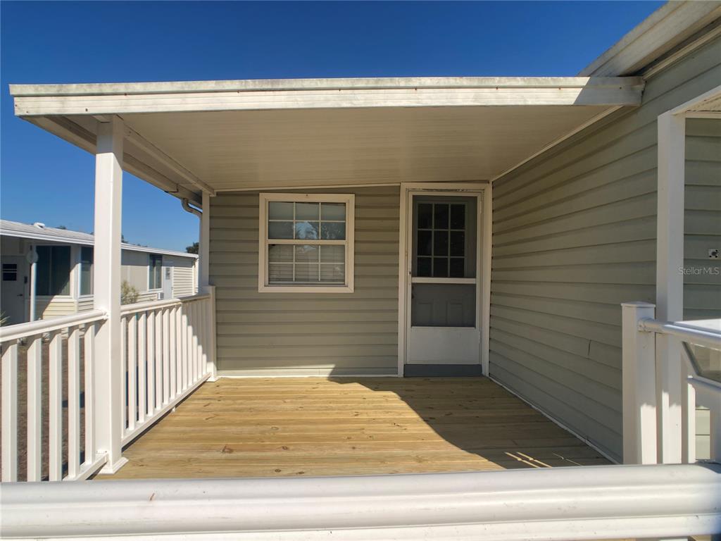 A covered wooden porch with white railings attached to the side of a mobile home — 1710 7TH STREET SW UNIT 44, RUSKIN, FL