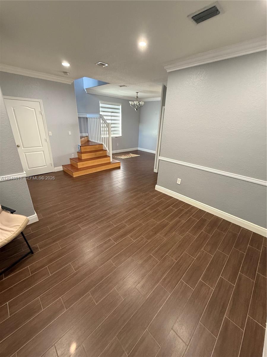 A room with wood-look tile flooring, a staircase with wooden steps, and light gray walls — 7353 NW 174th Ter # 107, Hialeah FL 33015, HIALEAH, FL