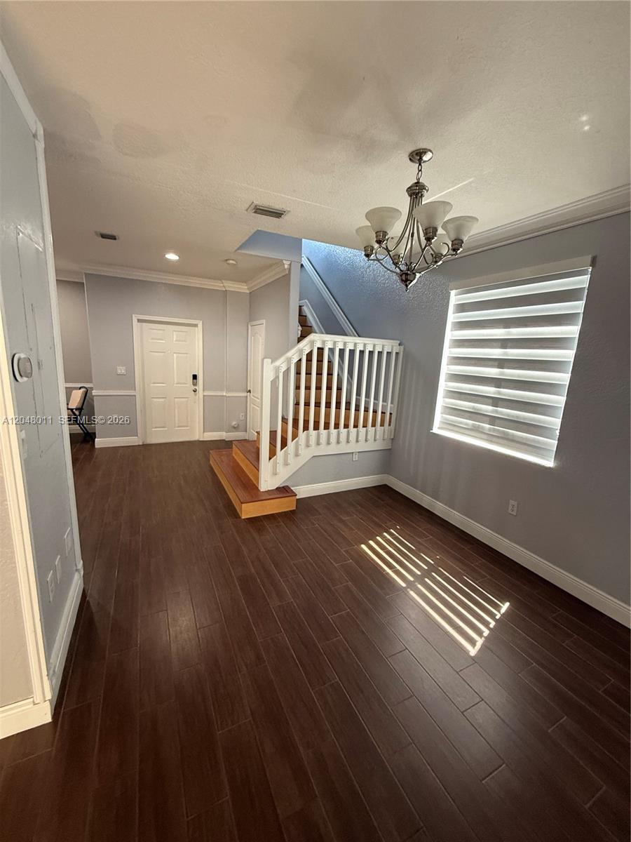 This entryway features dark wood flooring, a white staircase, and a hanging chandelier — 7353 NW 174th Ter # 107, Hialeah FL 33015, HIALEAH, FL