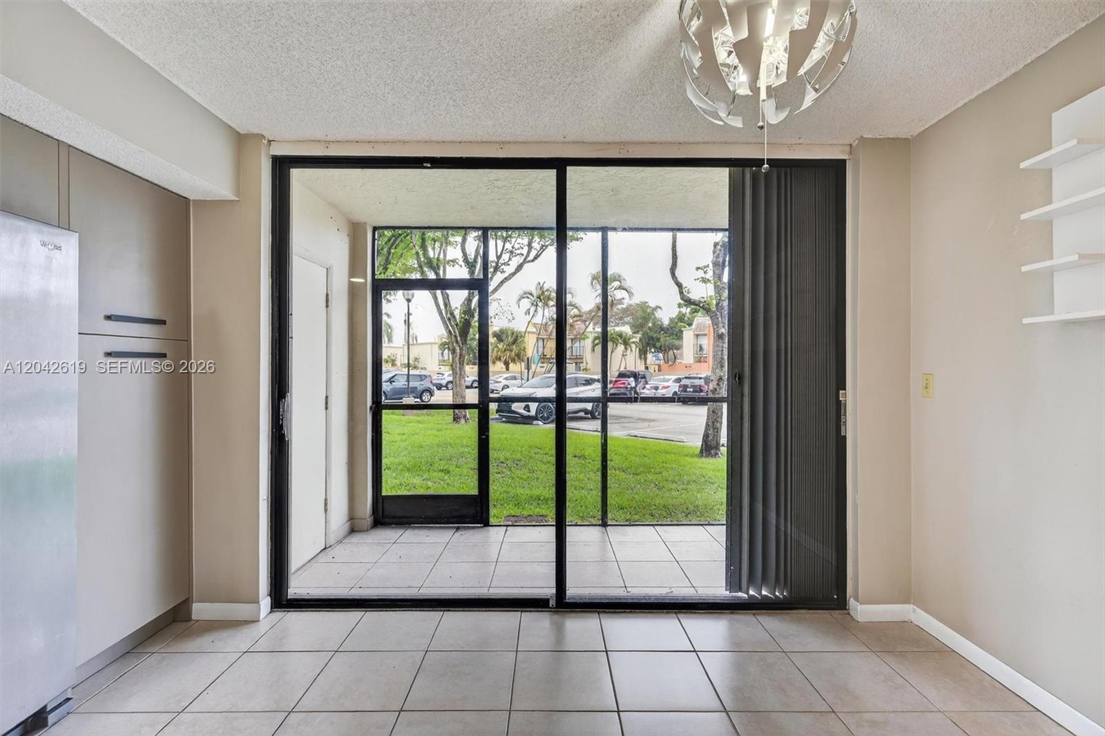 A room with tile flooring features a sliding glass door leading to a screened patio — 8065 SW 107th Ave # 106, Miami FL 33173, MIAMI, FL