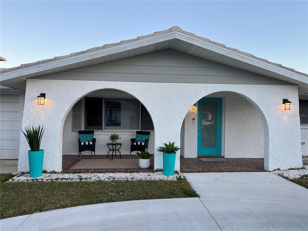 The exterior of a house features a white stucco facade with two arched entryways and a teal door — 4825 SHELL STREAM BOULEVARD, NEW PORT RICHEY, FL