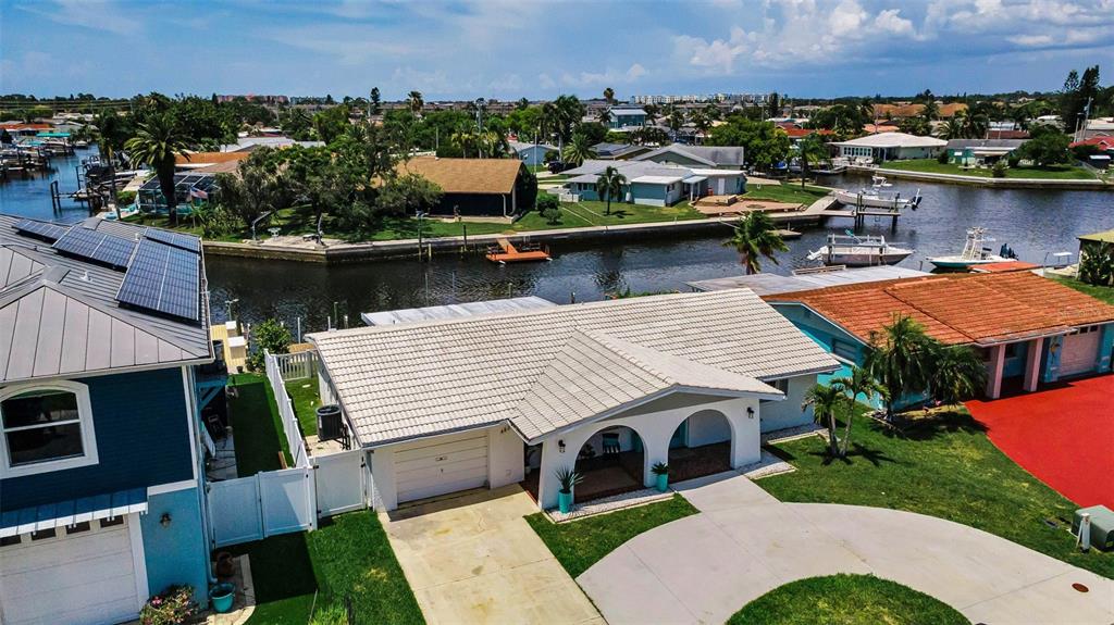 An aerial view shows a single-story house with a white tile roof and canal access — 4825 SHELL STREAM BOULEVARD, NEW PORT RICHEY, FL