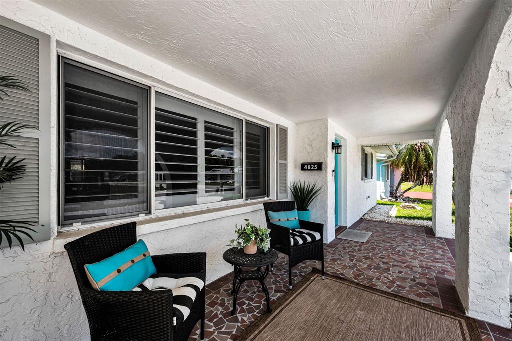 A covered patio features a tiled floor, two wicker chairs, and a large window — 4825 SHELL STREAM BOULEVARD, NEW PORT RICHEY, FL