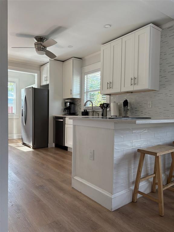 A kitchen features white cabinets, a tiled island, stainless steel appliances, and light wood flooring — 2570 LOMA LINDA STREET, SARASOTA, FL