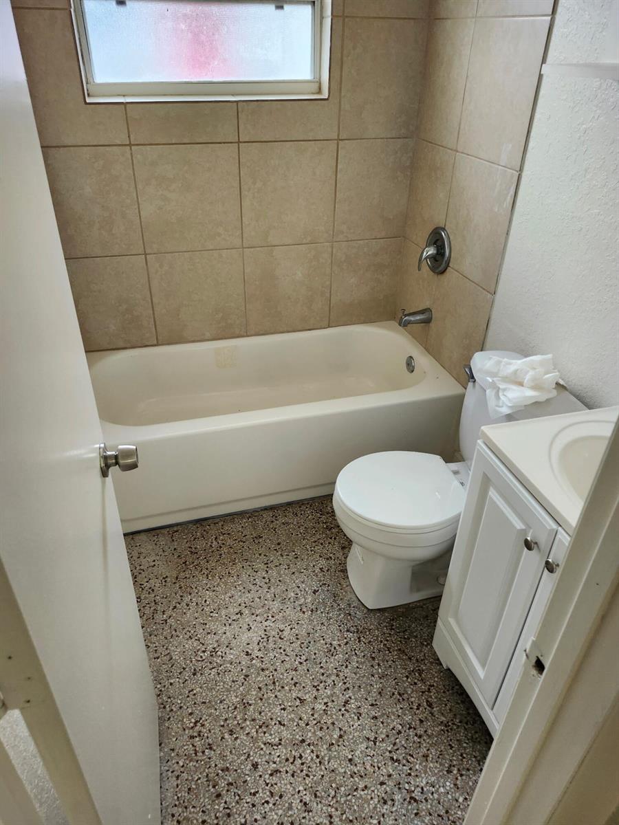 A small bathroom features a beige bathtub, a white toilet, and a vanity cabinet — 1401 G Terrace, Fort Pierce FL 34950, FORT PIERCE, FL